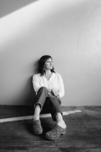 black and white photo of Caryn sitting against a wall