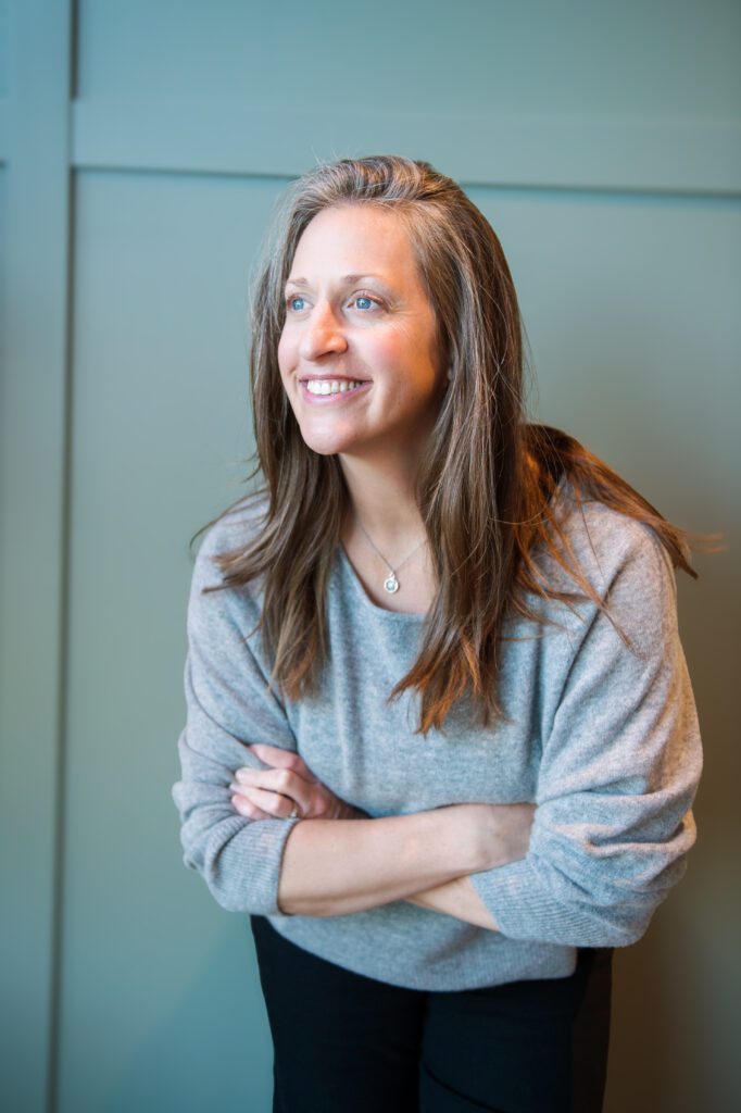 Caryn with crossed arms, leaning forward, looking off into distance
